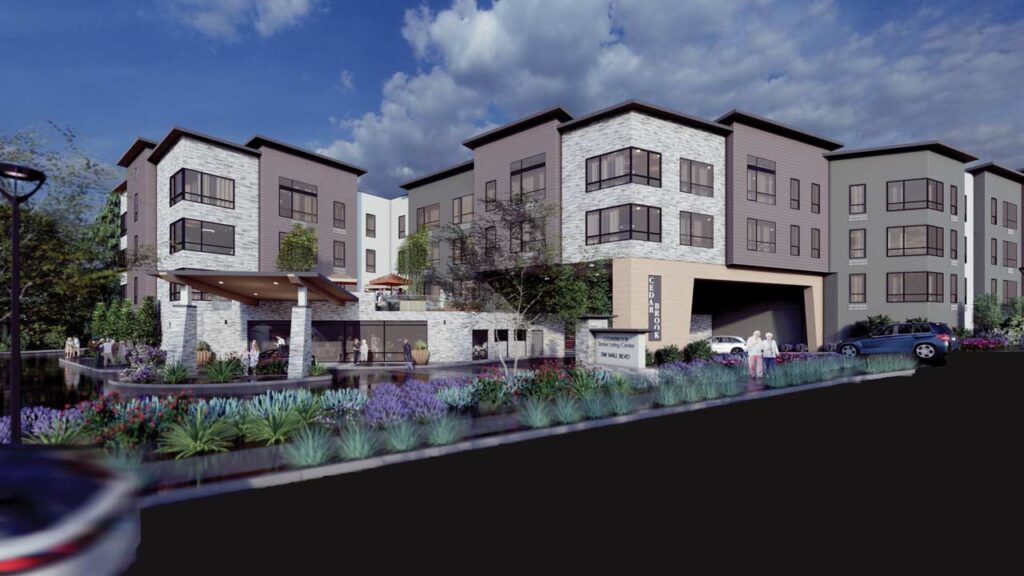 Modern apartment complex with four-story buildings, large windows, stone and wood facades, landscaped gardens with purple flowers, a swimming pool, and people walking near the entrance under a blue sky with scattered clouds.